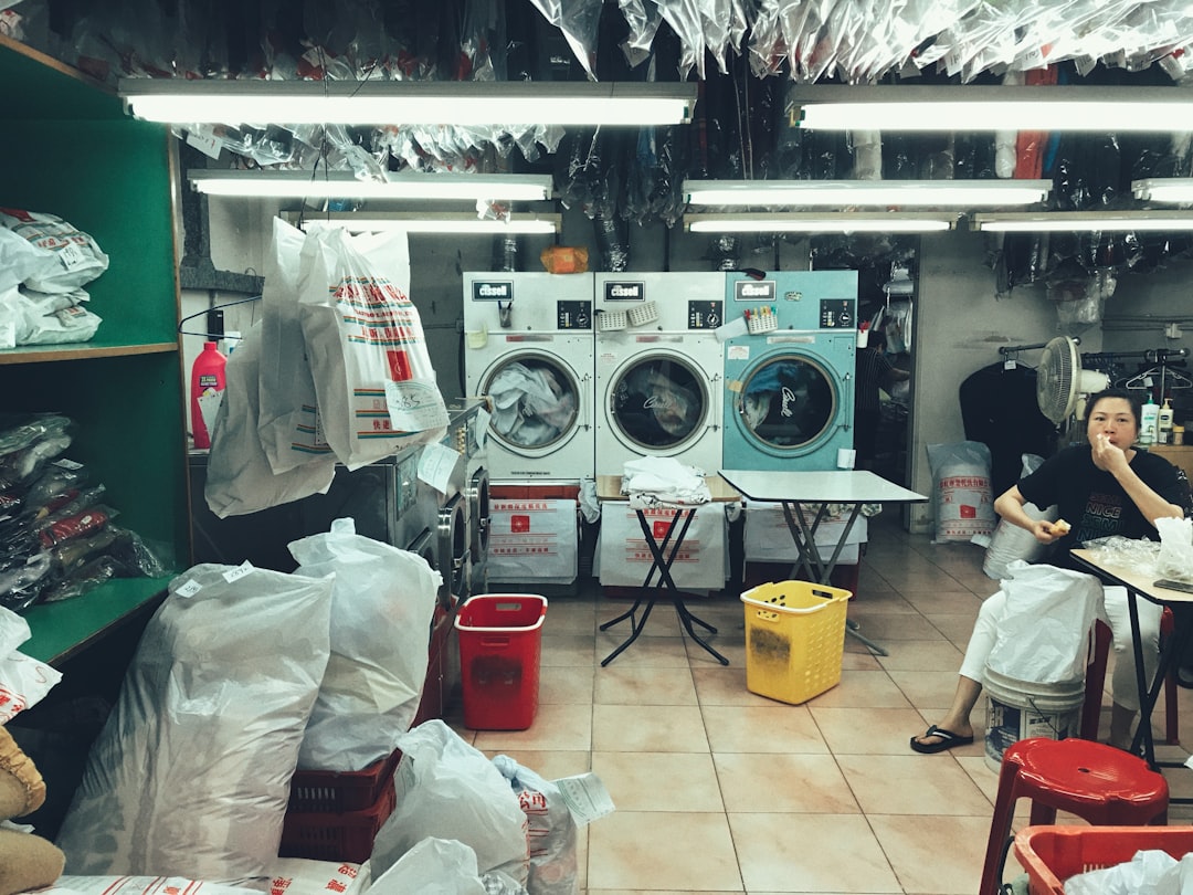 a-woman-sitting-in-front-of-a-washing-machine-4jsgbd15ytw