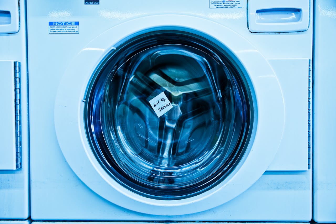 services-02 Close-up of an out-of-service washing machine in a laundromat with a blue tint.