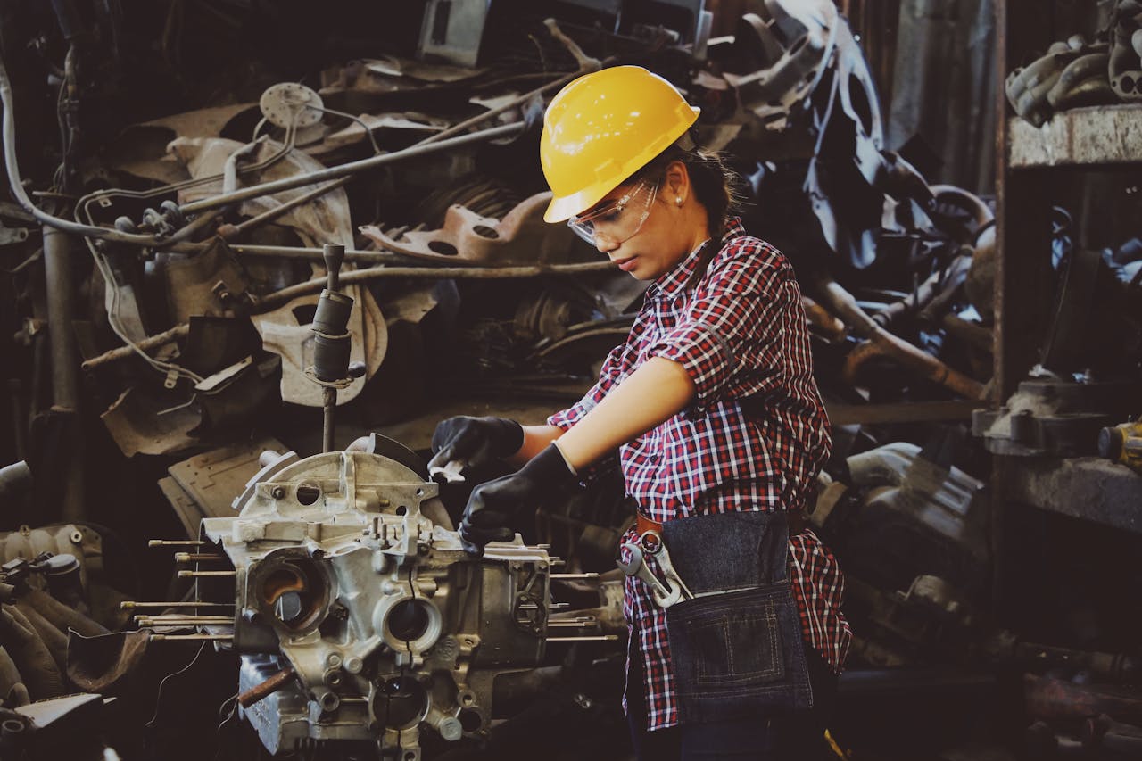 services-01 Woman engineer wearing safety gear, working on machine repair in an industrial setting.